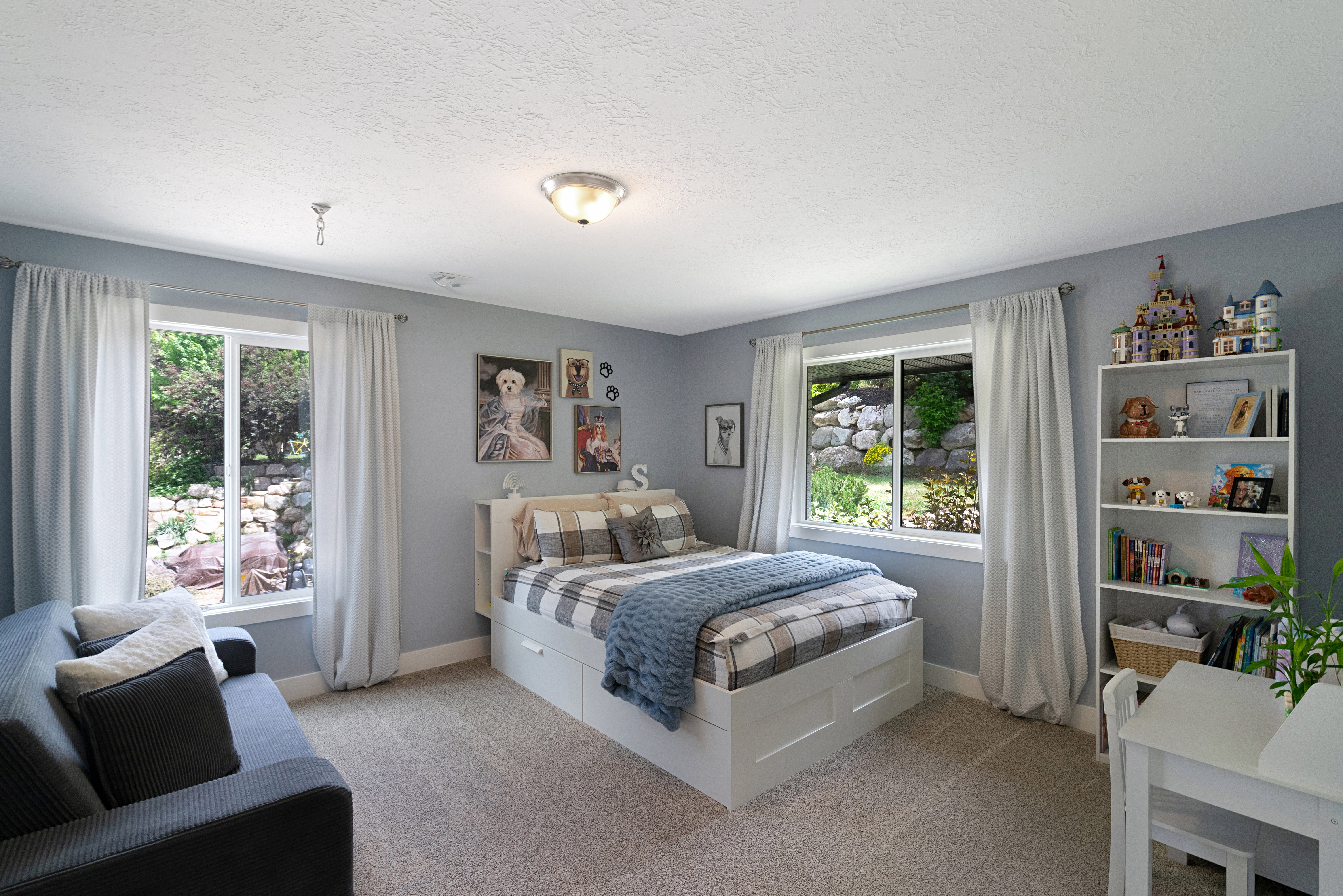 Interior room featuring two large windows with white trim, light gray walls, and textured carpeting