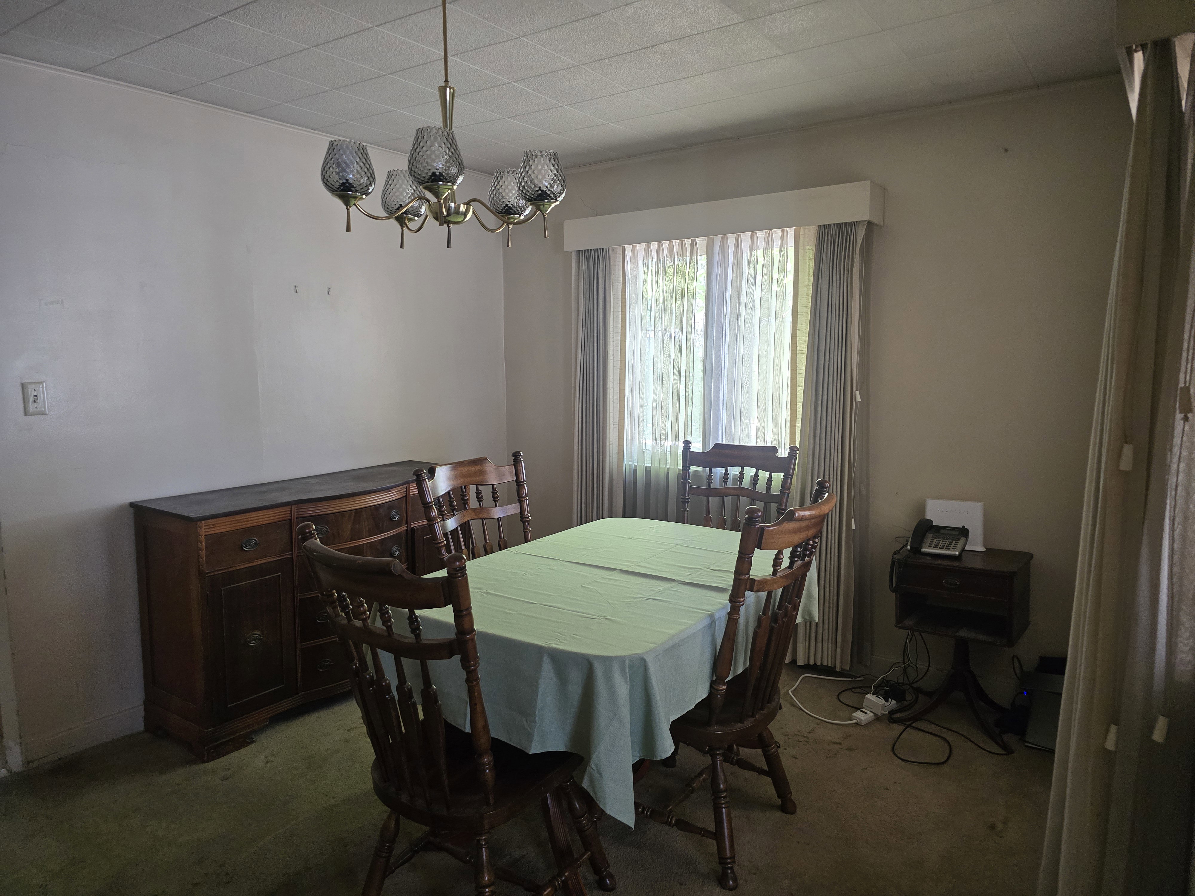 Dining area featuring a chandelier, window with sheer and opaque drapes, and carpeted flooring