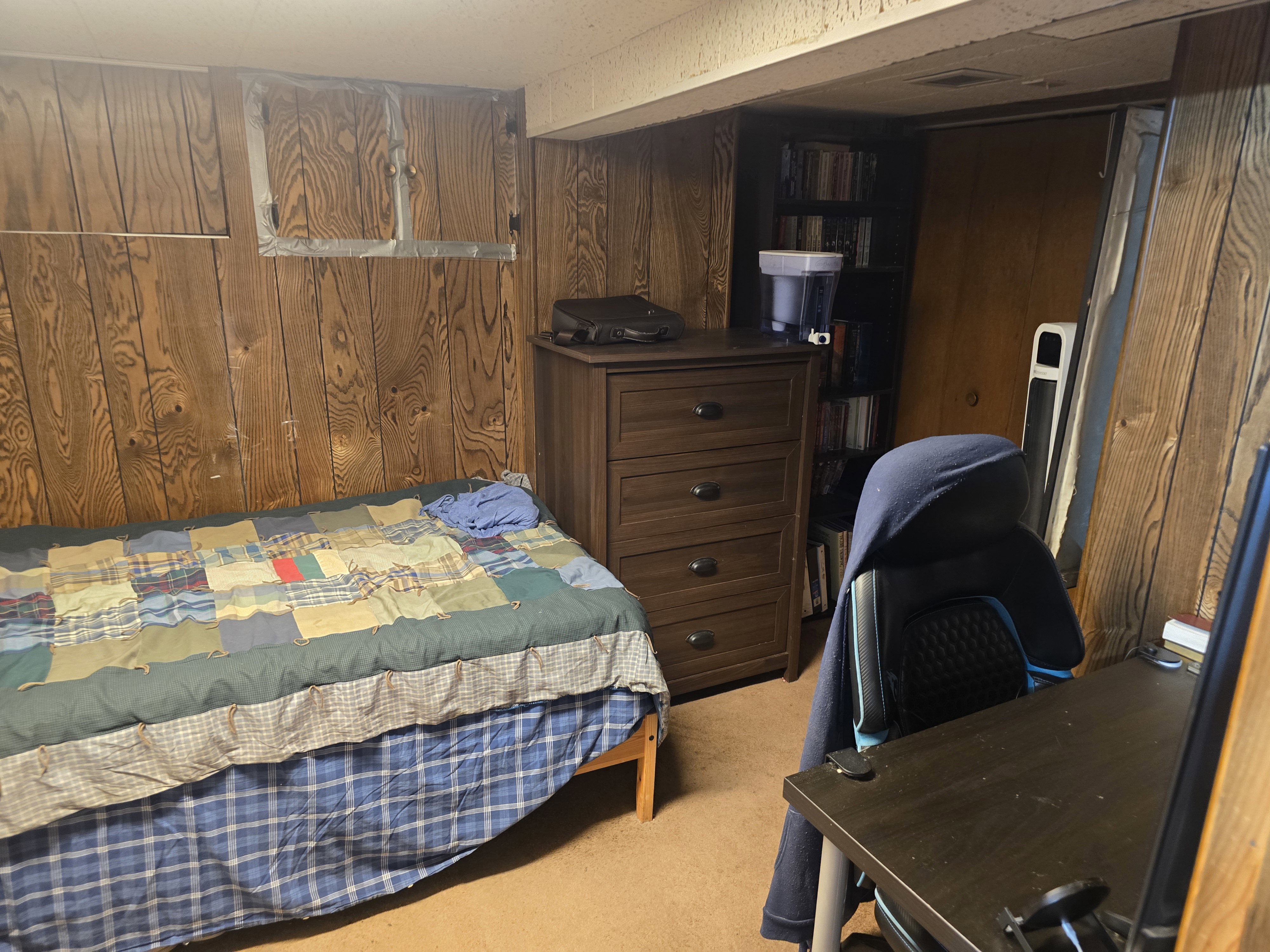 Wood-paneled room featuring textured ceiling, carpeted flooring, and a built-in storage unit
