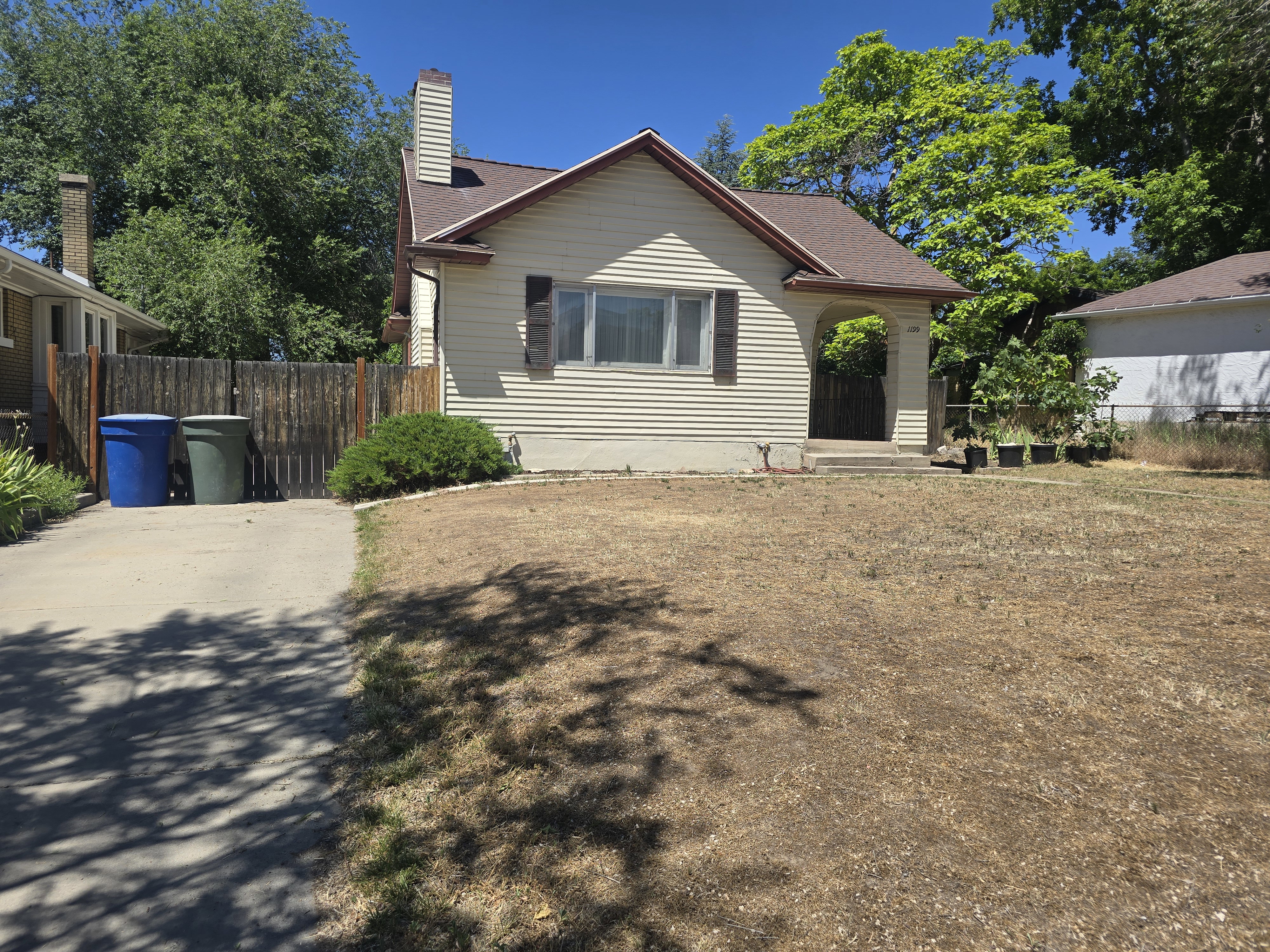 Single-story residence featuring horizontal siding and a prominent chimney. Driveway leading to the back of the lot