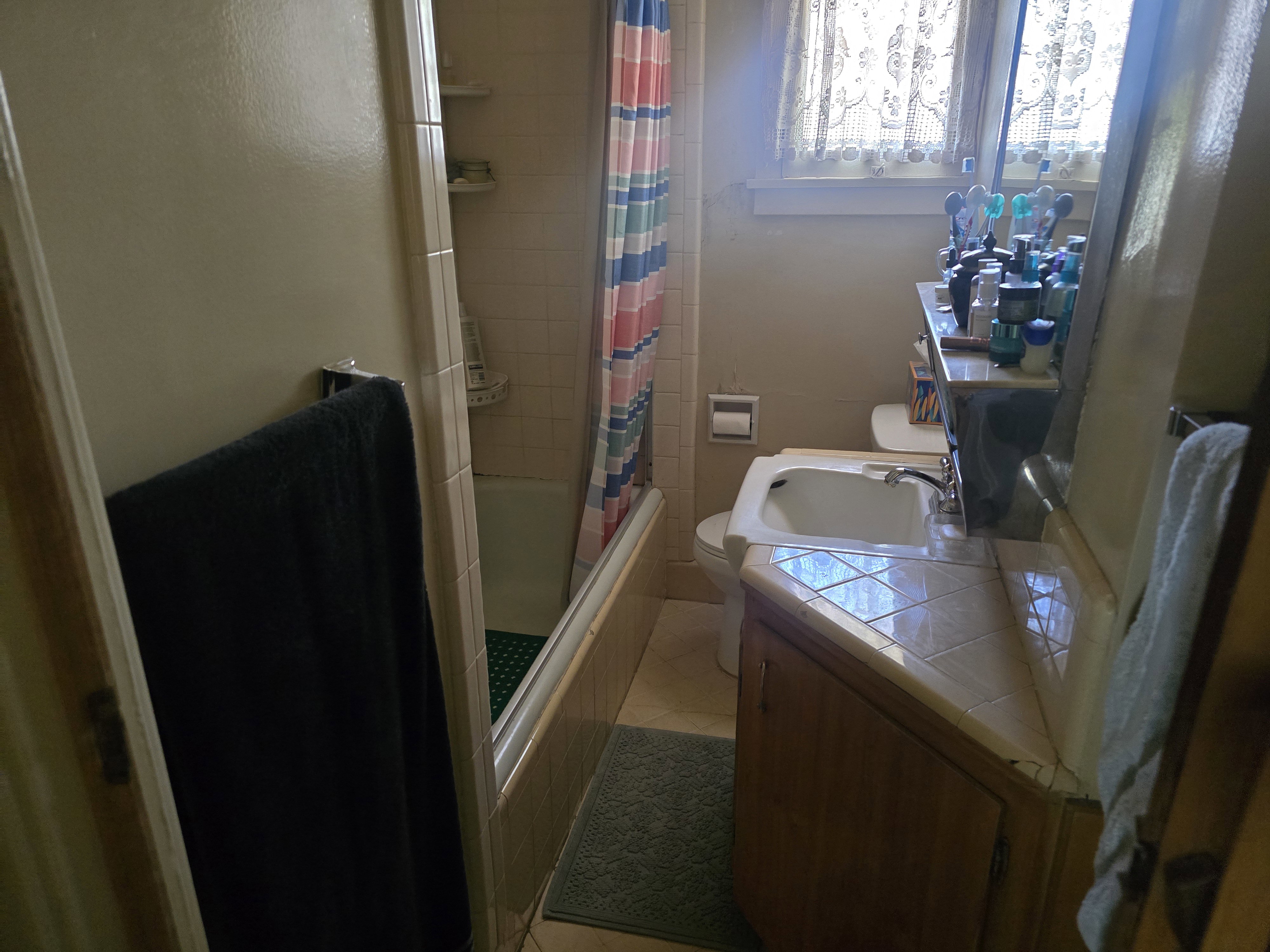 Bathroom featuring a tile-top vanity with integrated sink, wood-finish cabinetry, and a full-size bathtub with tile surround