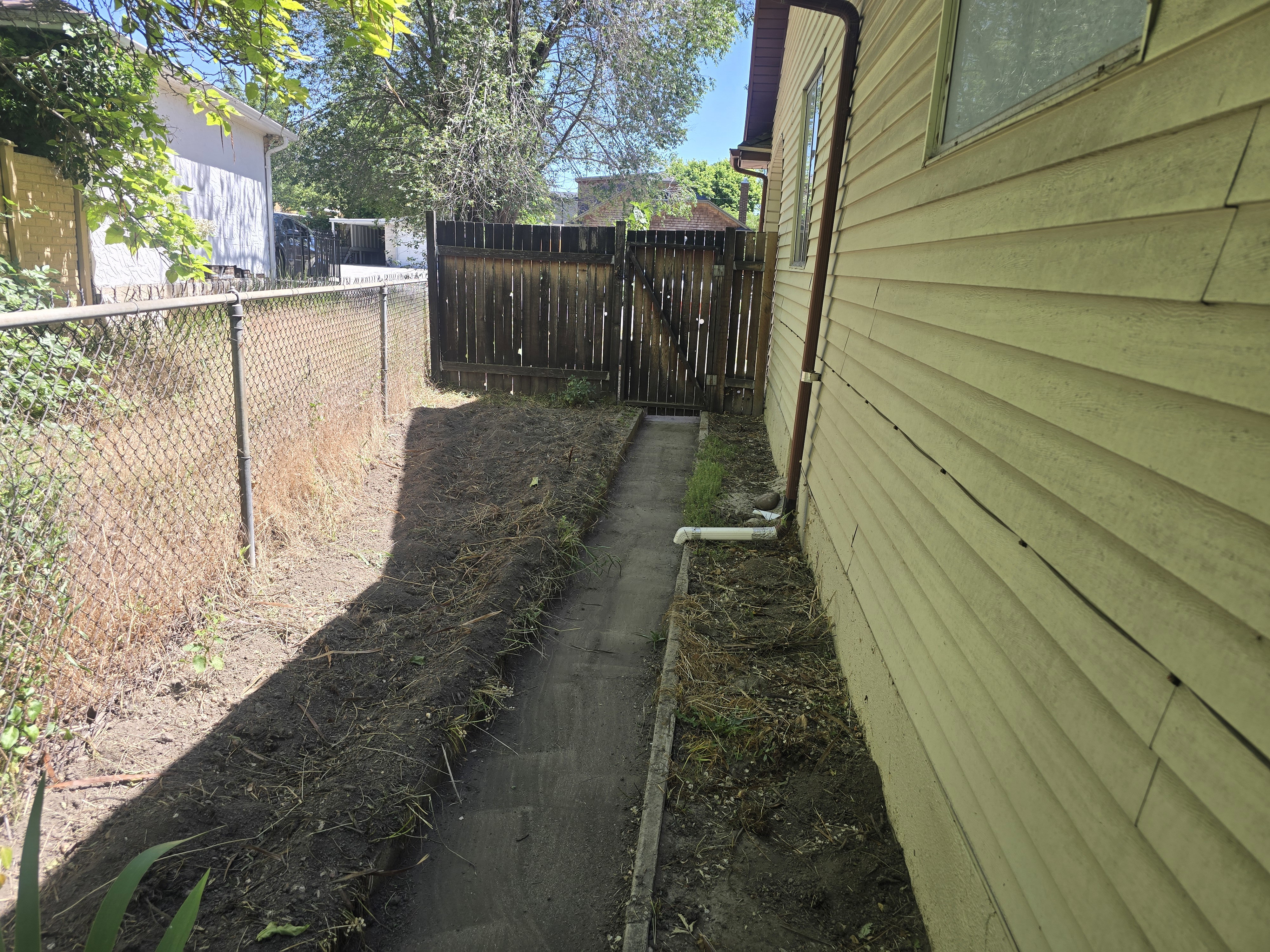 Side yard featuring a chain-link fence, a wooden privacy fence, and horizontal siding