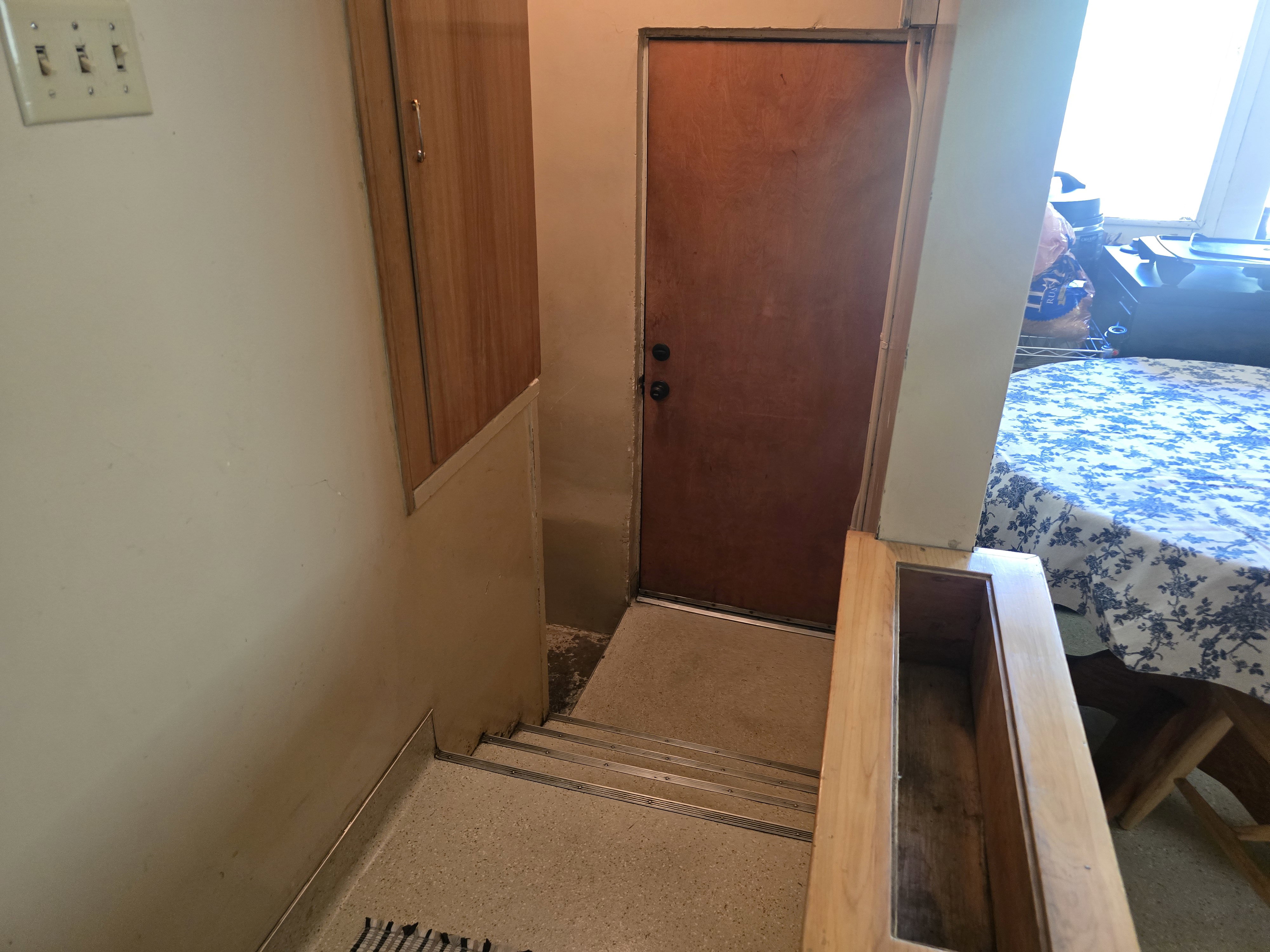 Wood-finish wall cabinetry with metal hardware. Door leading to the back yard.