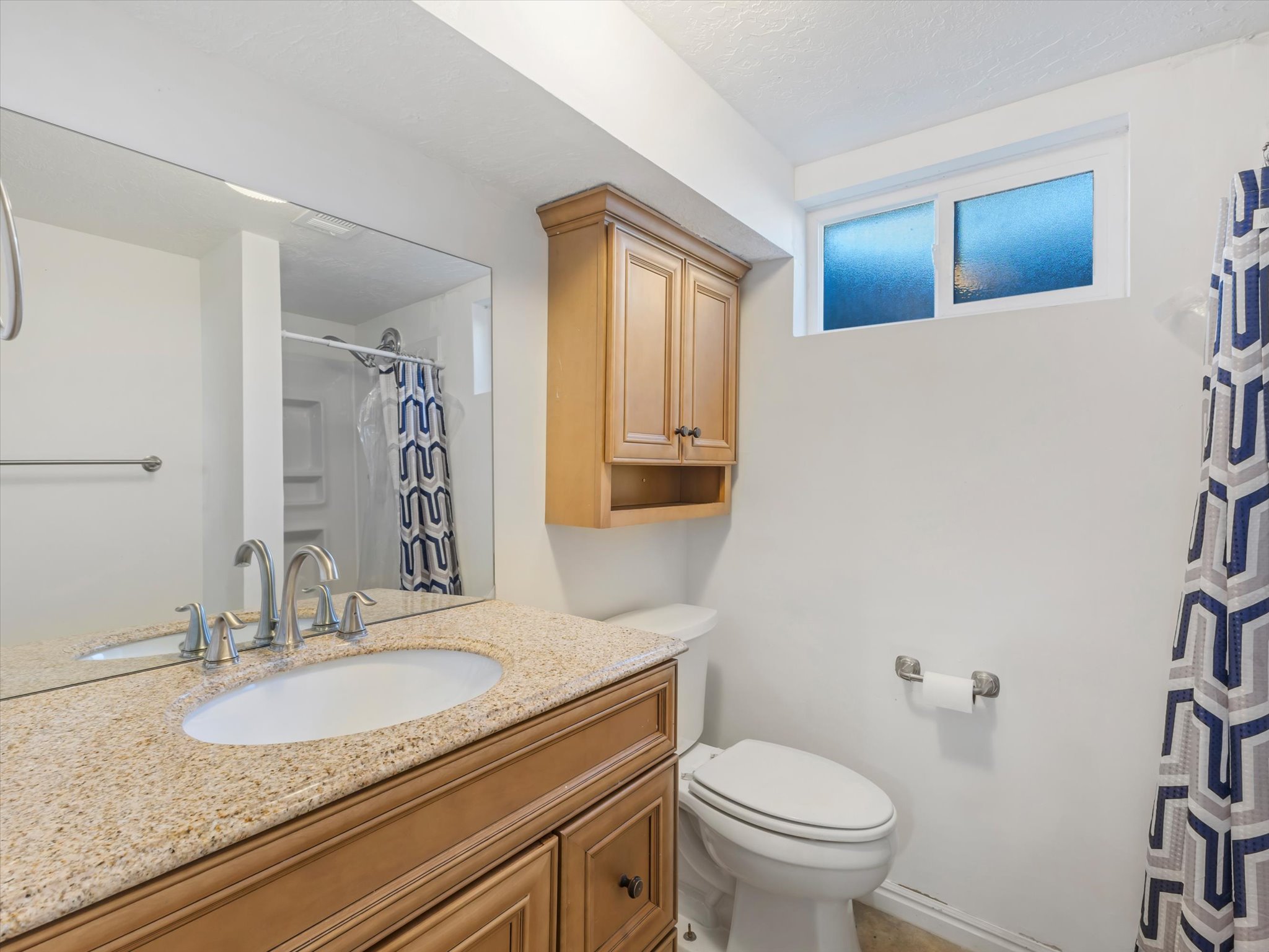 Bathroom vanity with an integrated oval sink, stone countertop, and chrome faucet