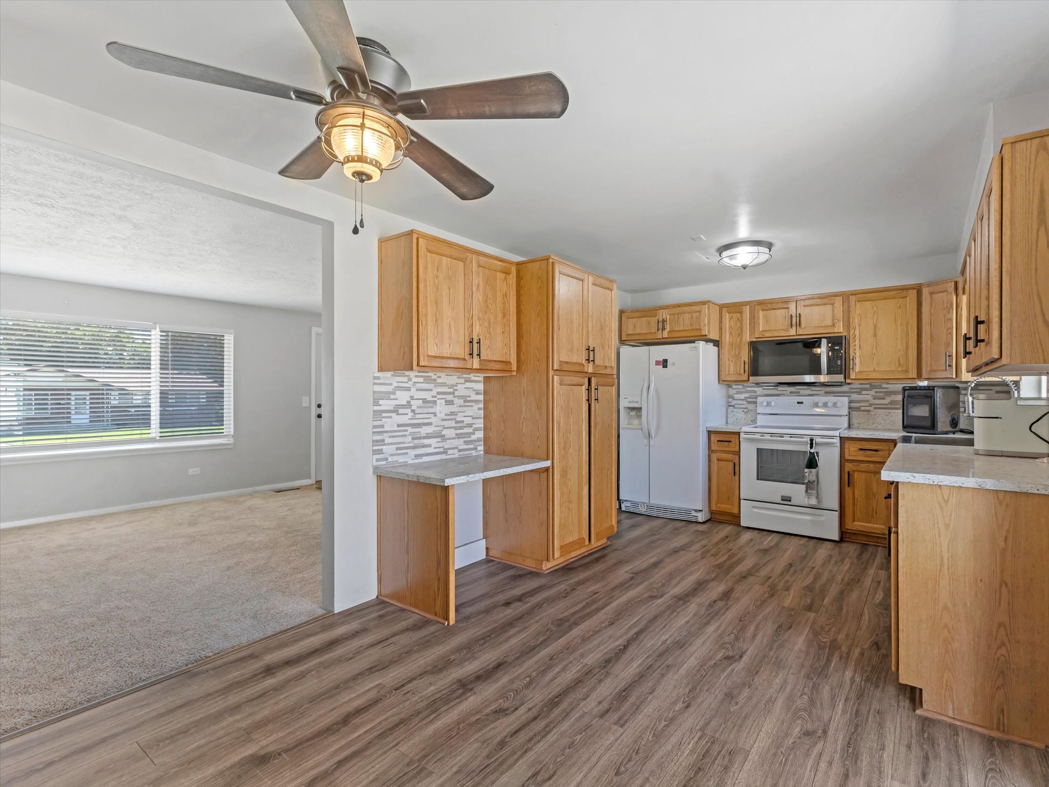 Full kitchen featuring wood-finish cabinetry, light-toned countertops, and a tiled backsplash