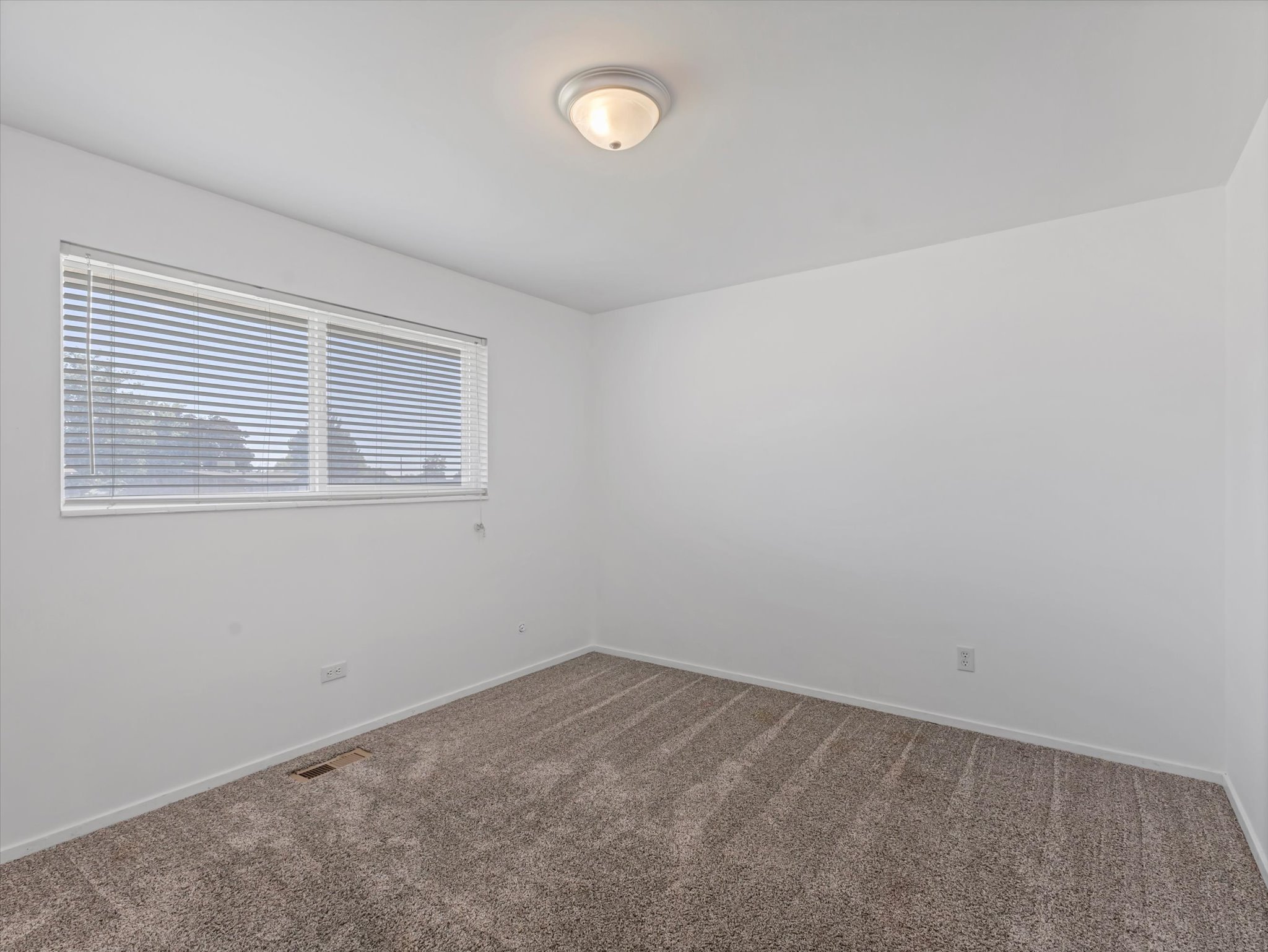 Room featuring neutral wall tones, textured carpeting, and a window with horizontal blinds
