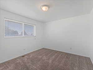 Room featuring neutral wall tones, textured carpeting, and a window with horizontal blinds