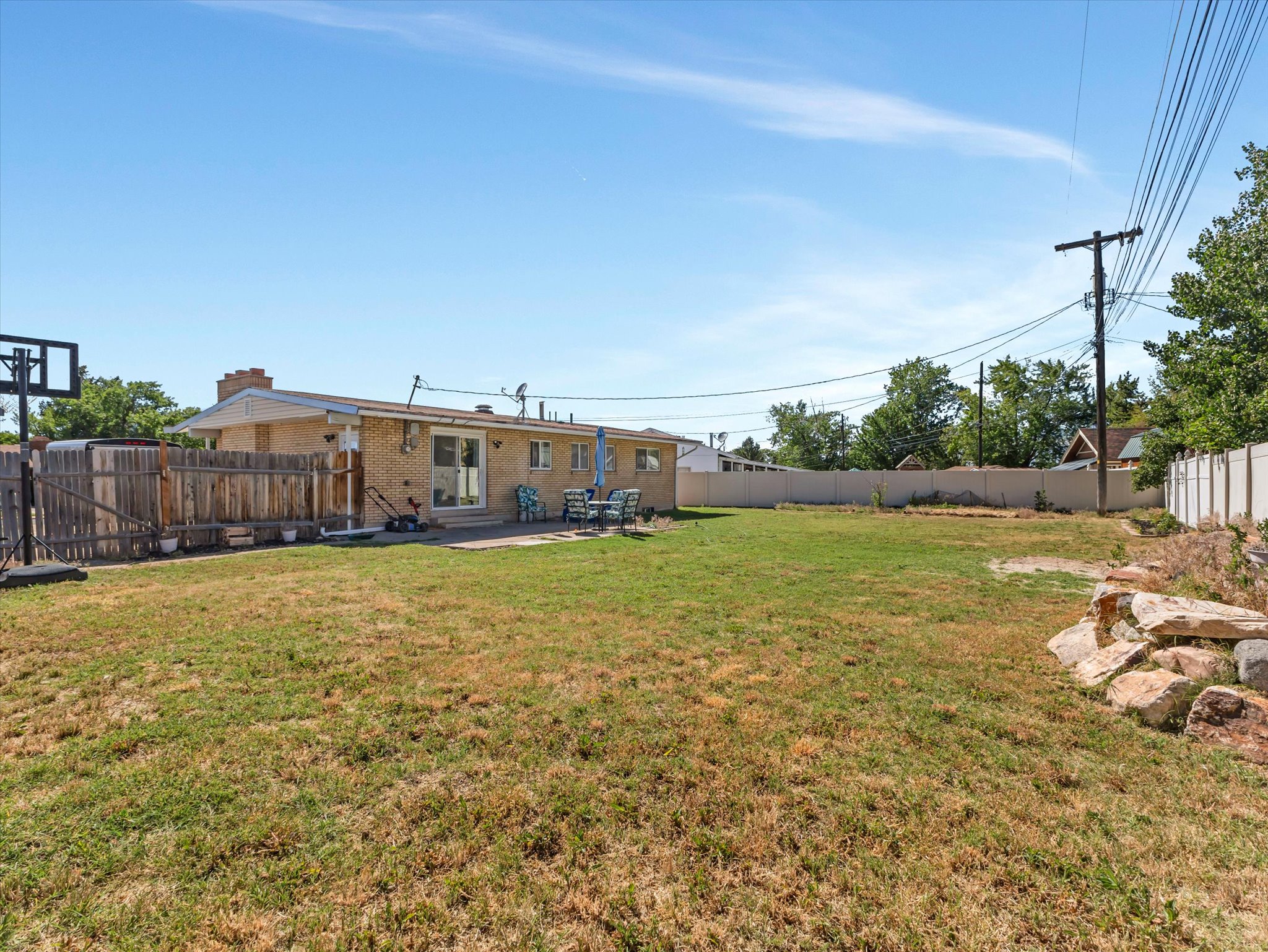 Expansive backyard with a brick exterior home, featuring a concrete patio, sliding glass door access, and a wood privacy fence
