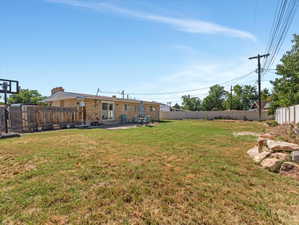 Expansive backyard with a brick exterior home, featuring a concrete patio, sliding glass door access, and a wood privacy fence