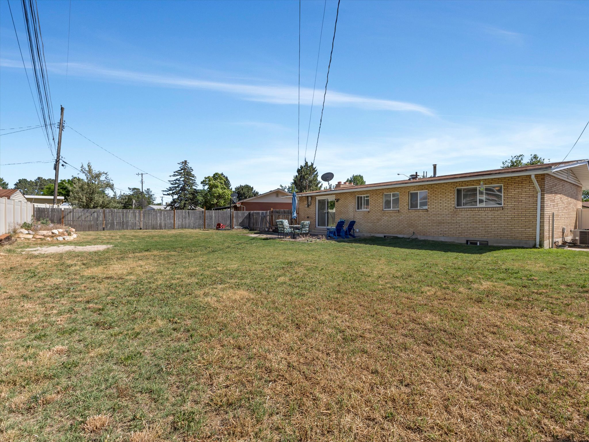 Expansive backyard featuring a brick exterior, a patio area, a sliding glass door, and a full perimeter fence