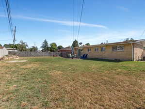 Expansive backyard featuring a brick exterior, a patio area, a sliding glass door, and a full perimeter fence