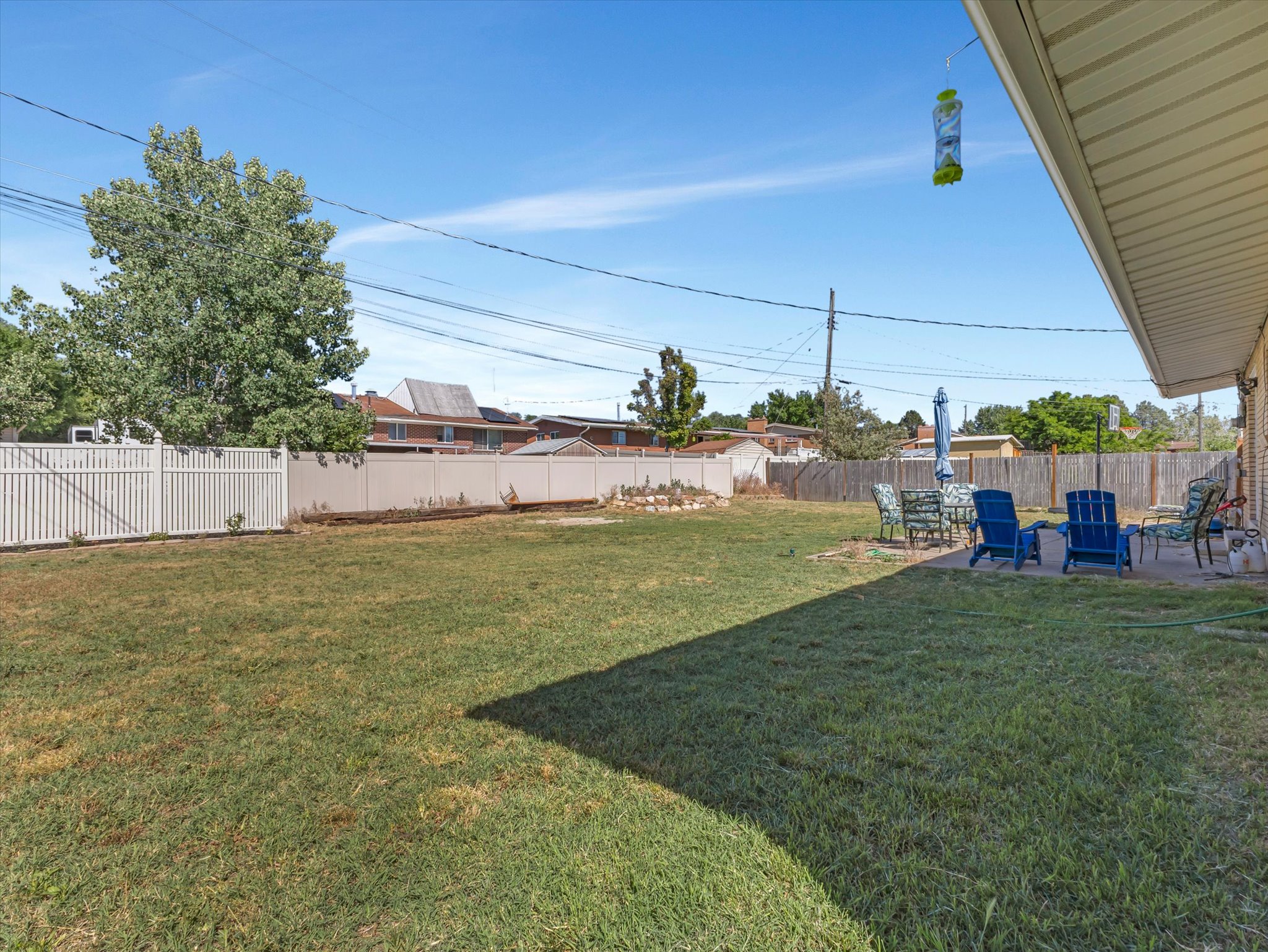 Expansive backyard featuring a large grass lawn, perimeter fencing, and a concrete patio