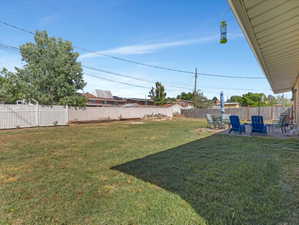 Expansive backyard featuring a large grass lawn, perimeter fencing, and a concrete patio