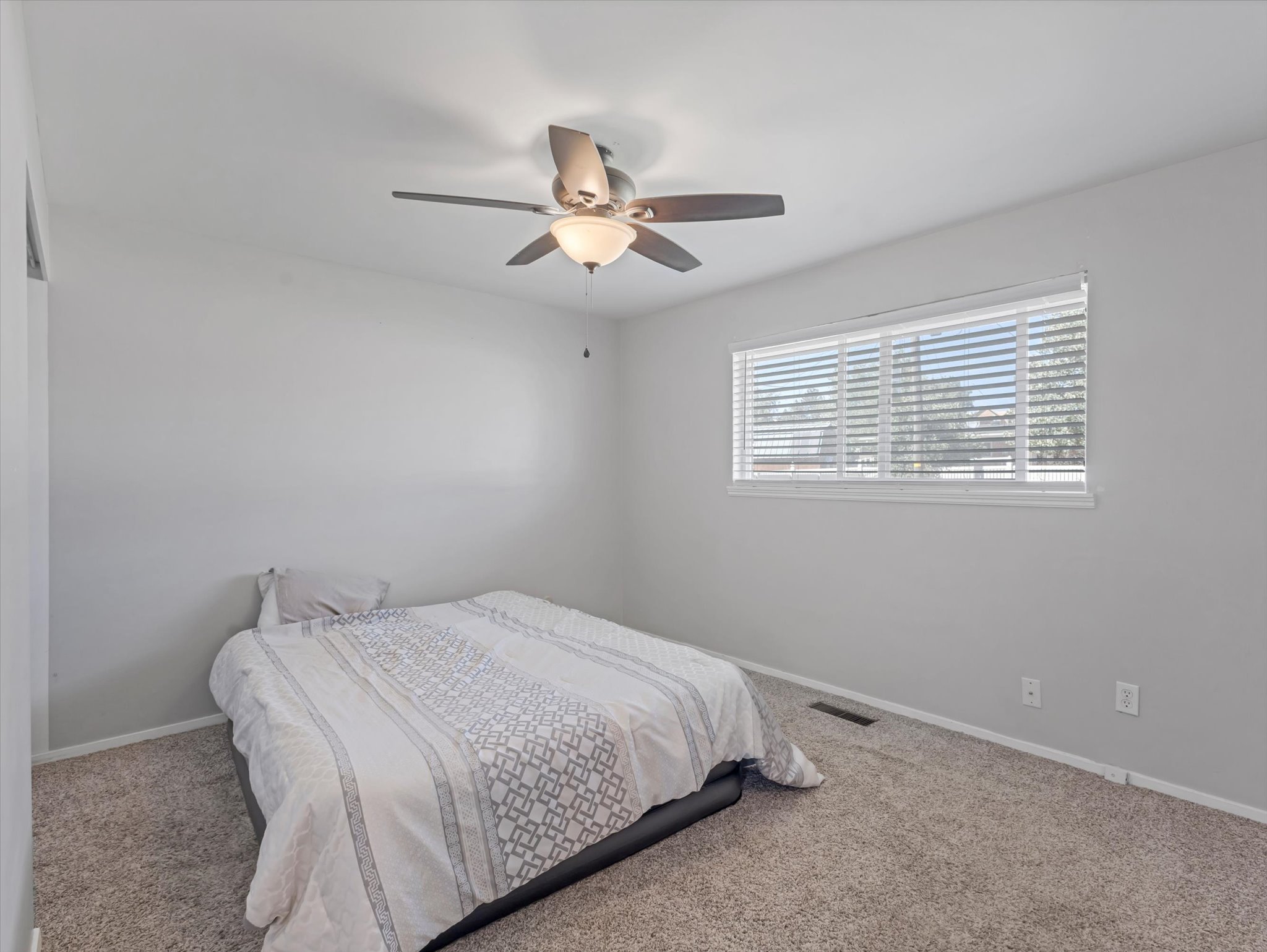 Carpeted room featuring a ceiling fan with integrated lighting, a window with horizontal blinds, and light gray wall paint