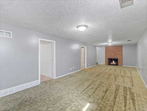 Spacious room with plush carpeting, featuring a brick-surround fireplace
