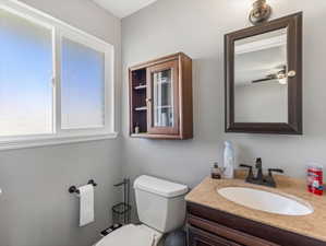 Bathroom featuring a wood-finish vanity with an integrated white sink, a stone-finish countertop, and a dark bronze-finish faucet