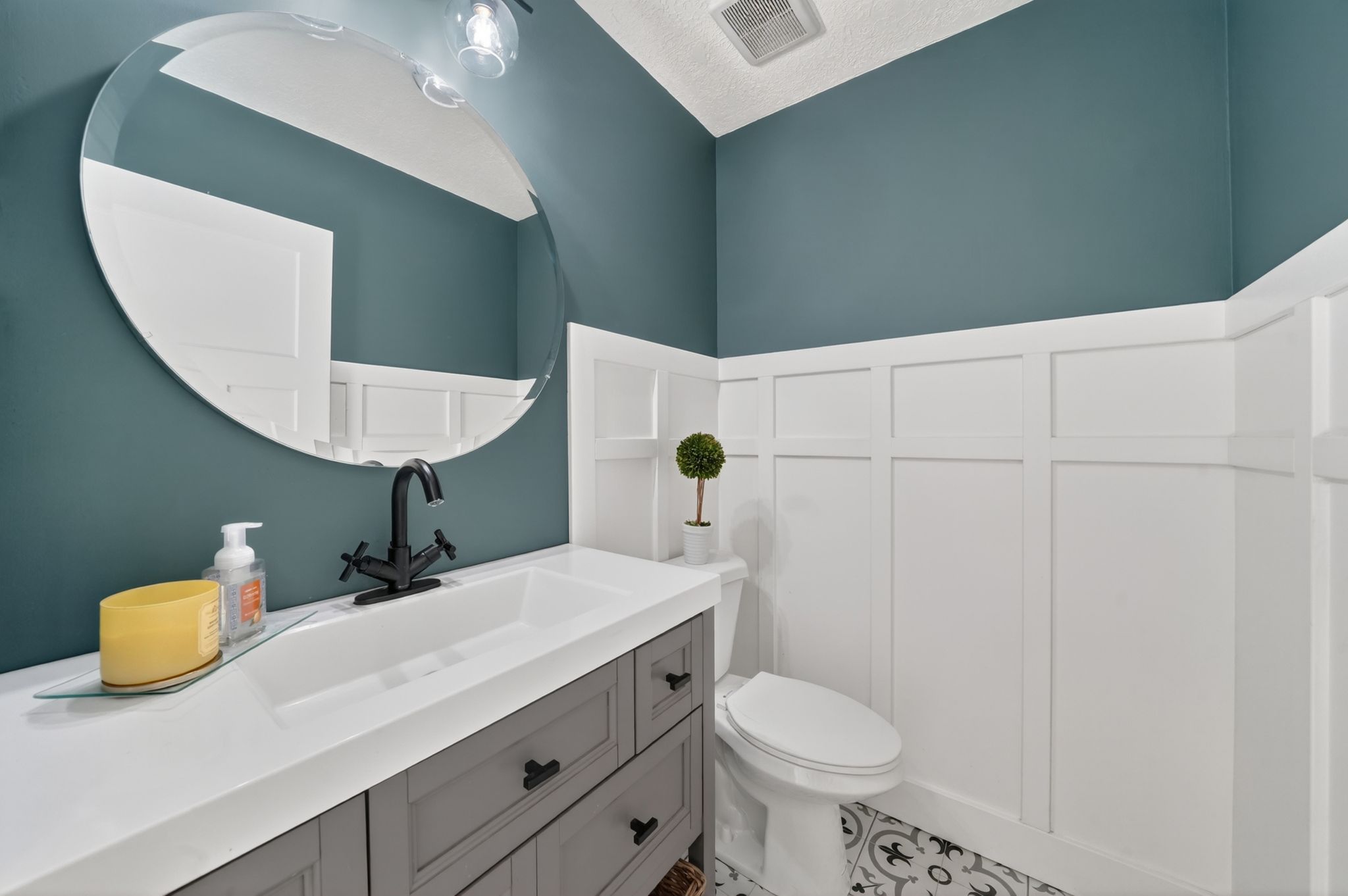 Modern bathroom featuring a single vanity with integrated sink, matte black faucet, and gray cabinetry
