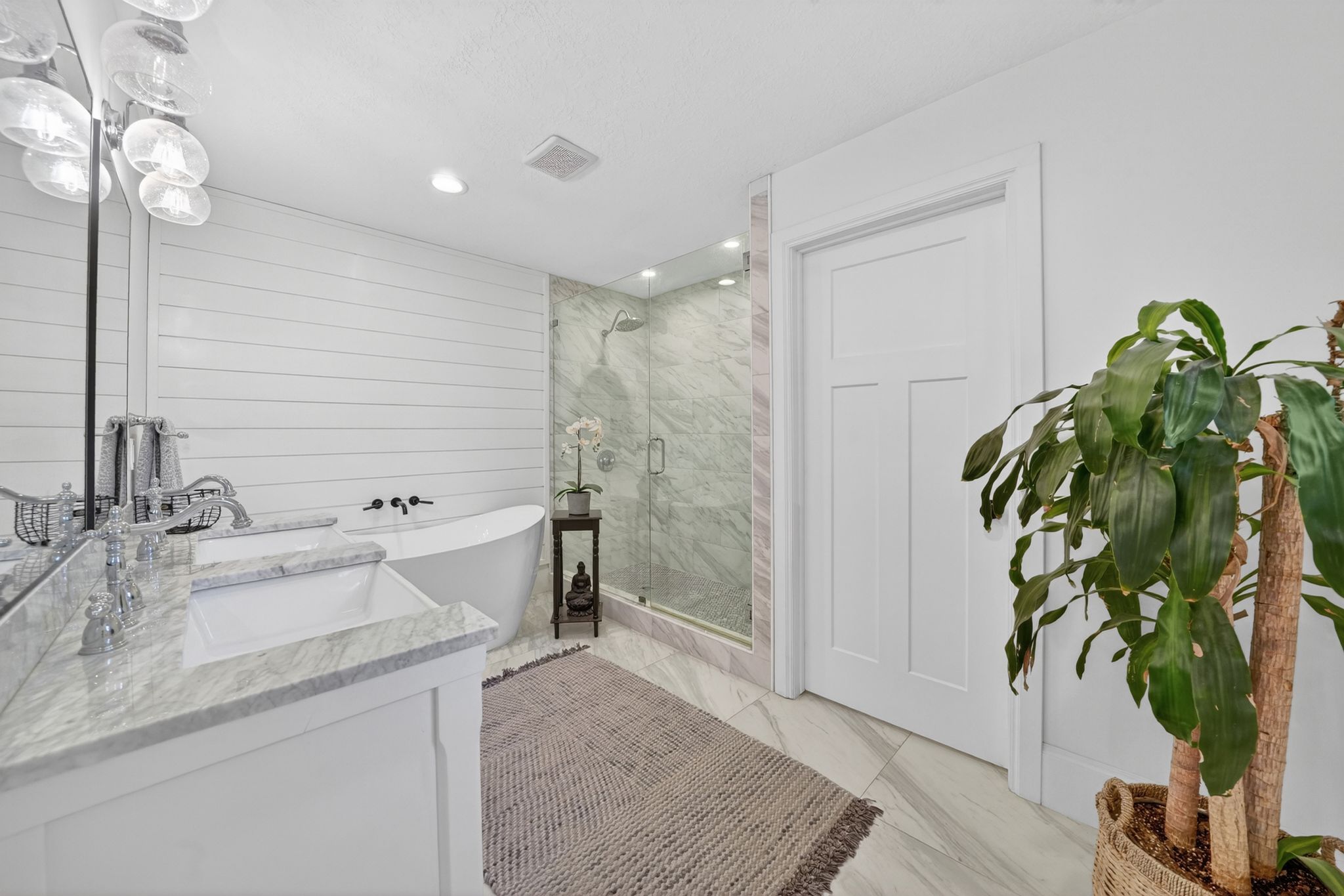Freestanding soaking tub complemented by a glass-enclosed shower with tiled walls