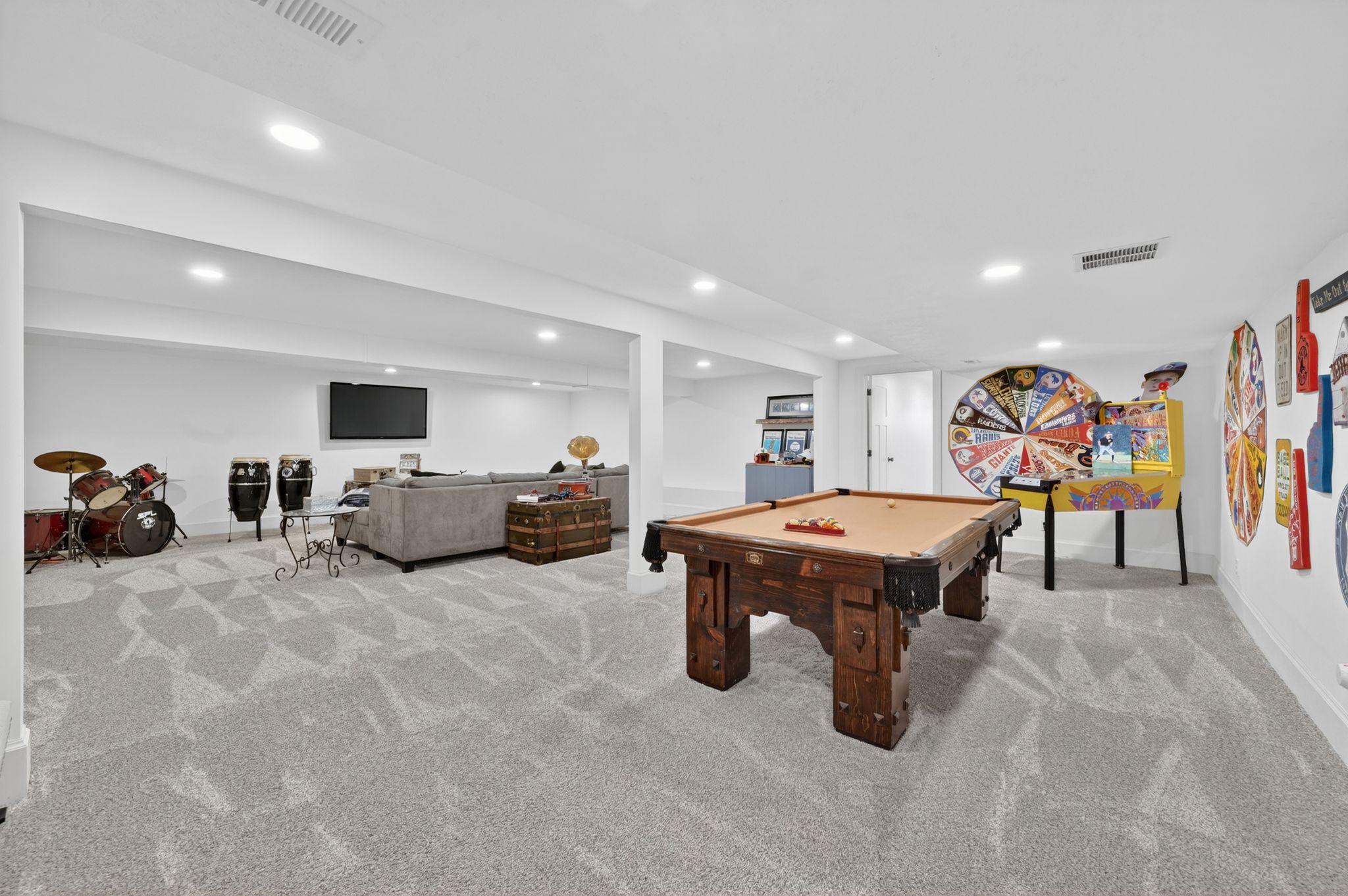 Spacious recreation room featuring light gray patterned carpeting, recessed lighting, and white walls