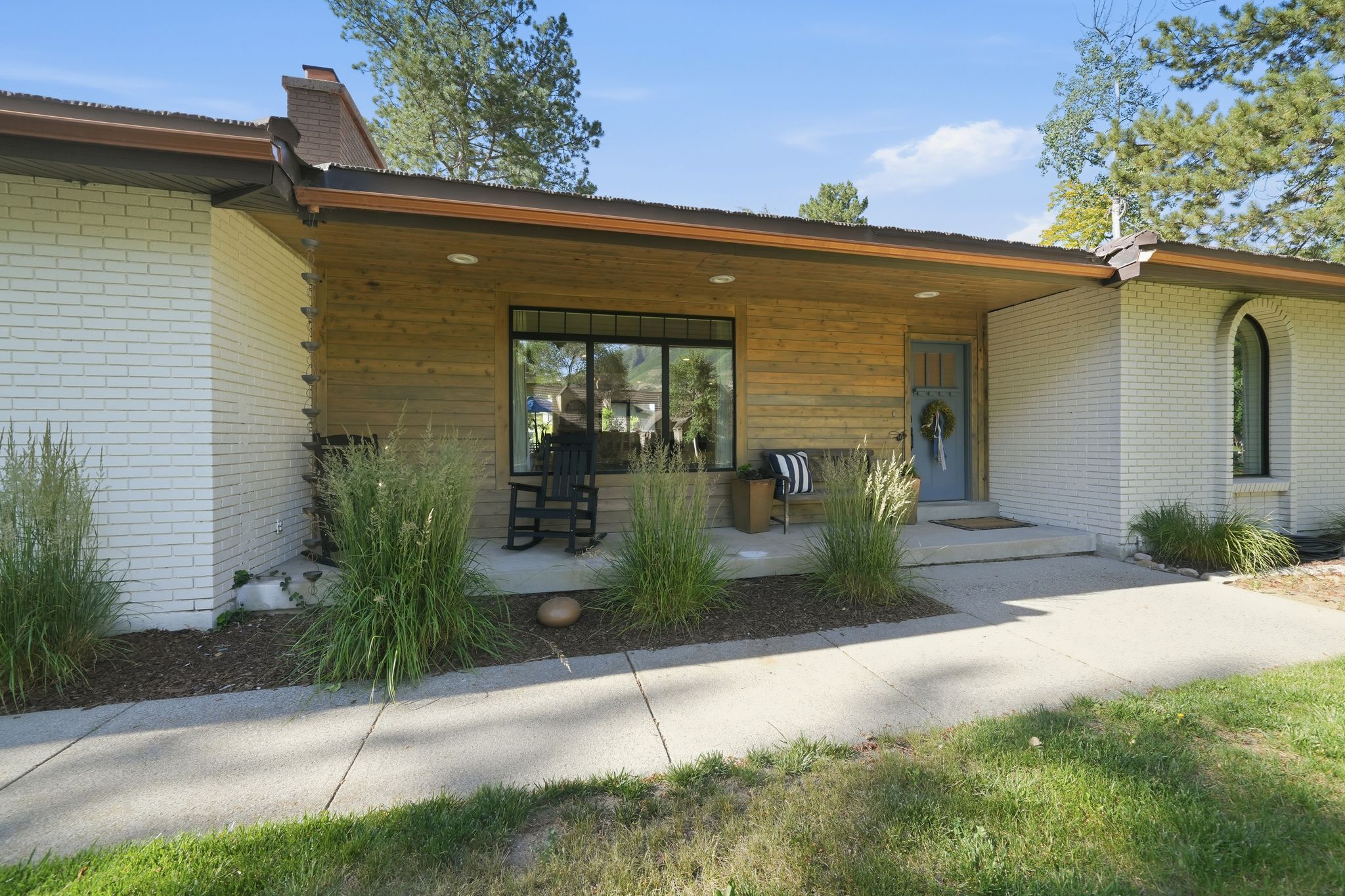 Mid-century modern exterior featuring white painted brick and horizontal wood paneling
