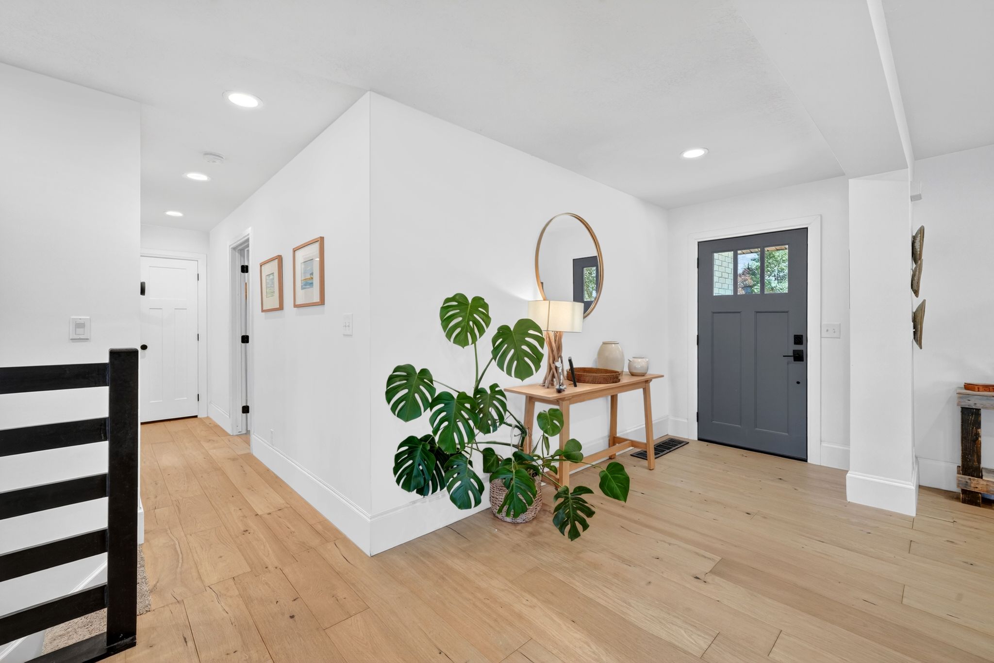 Entryway featuring a charcoal gray door with glass paneling, wood-finish flooring, recessed lighting, and white baseboards