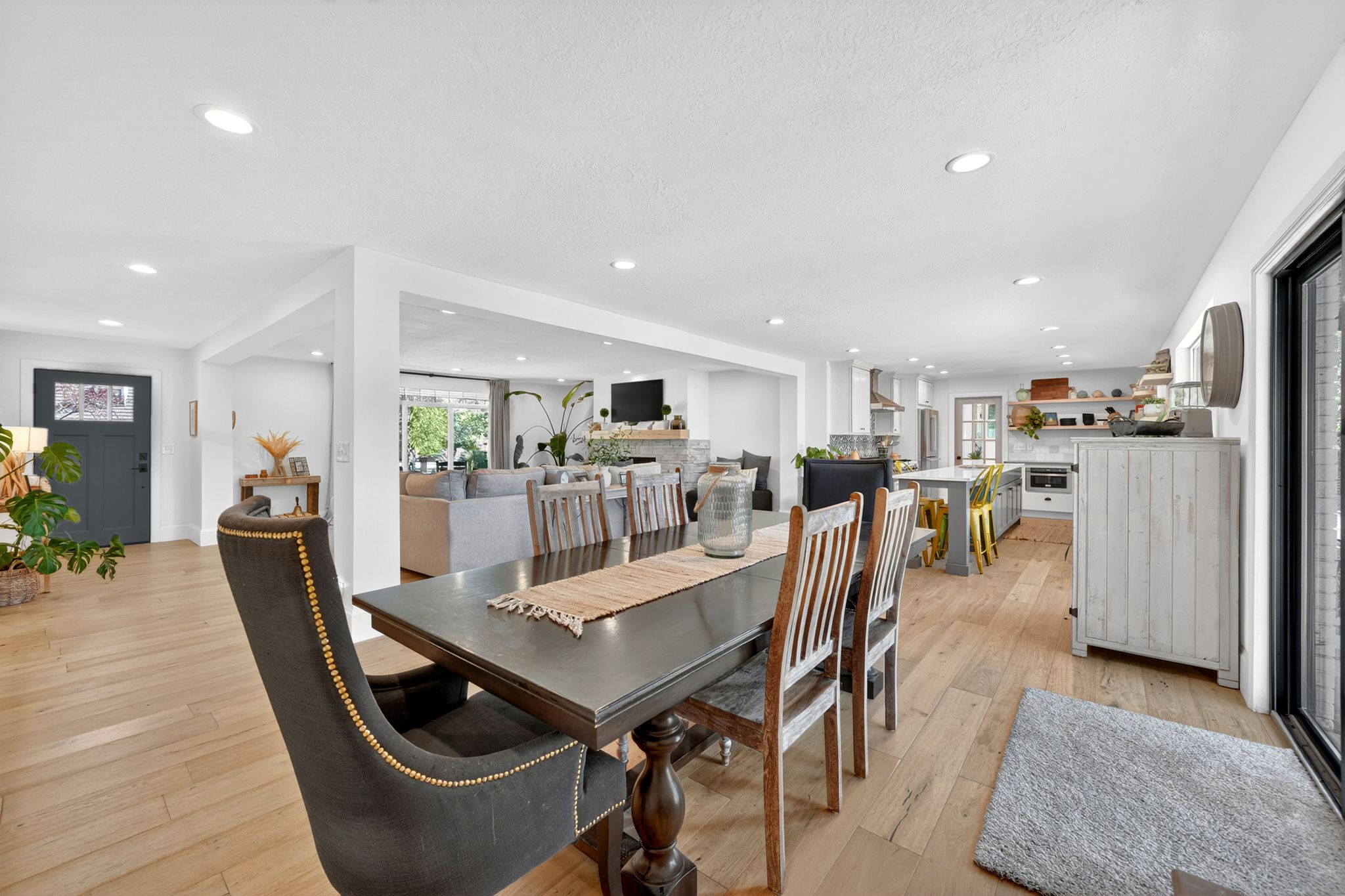 Open concept living space featuring wood-finish flooring, recessed lighting, a modern entry door with decorative glass, and a kitchen with an island