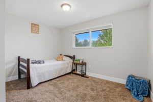 Bedroom featuring light gray walls, brown textured carpeting, and white baseboards