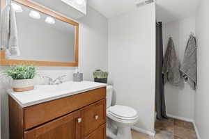 Bathroom featuring a wood-finish vanity with a white countertop, an integrated sink, and a framed mirror