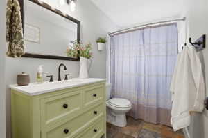 Bathroom featuring a green vanity with a white countertop, dark bronze-finish hardware, a rectangular mirror, and an overhead vanity light fixture