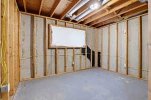 Unfinished room featuring exposed wooden stud framing, concrete walls, an exposed ceiling with ductwork, and a concrete floor