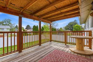 Expansive covered wood deck featuring natural wood railing, structural posts, and an exposed wood beam ceiling