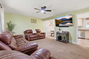 Spacious living area featuring neutral carpeting and a ceiling fan with integrated lighting
