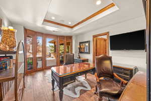 Office area with wood-type flooring, recessed lighting, a raised ceiling, and ornamental molding