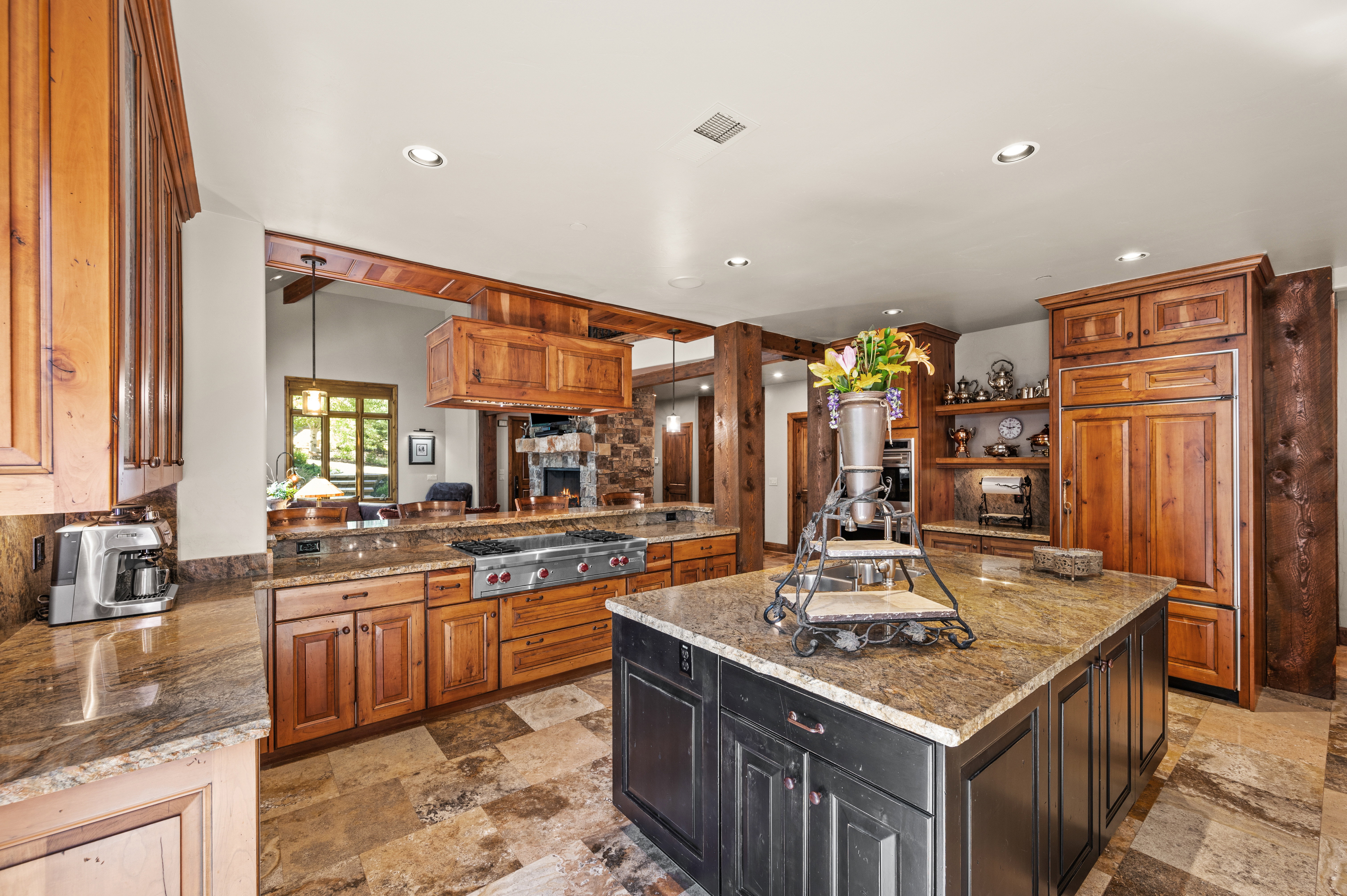 Dual tone kitchen with dark stone countertops, decorative light fixtures, open shelves, a center island, and dual tone cabinets
