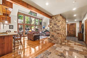 Living room featuring recessed lighting, vaulted ceiling with beams, and light stone finish floors