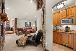 Living area featuring a fireplace, vaulted ceiling, light colored carpet, arched walkways, and recessed lighting