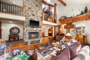 Living area with a stone fireplace, wood finished floors, recessed lighting, and lofted ceiling