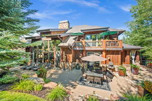Rear view of house featuring a patio area, board and batten siding, outdoor dining space, and a balcony