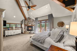 Bedroom featuring access to exterior, light carpet, ceiling fan, a stone fireplace, and recessed lighting