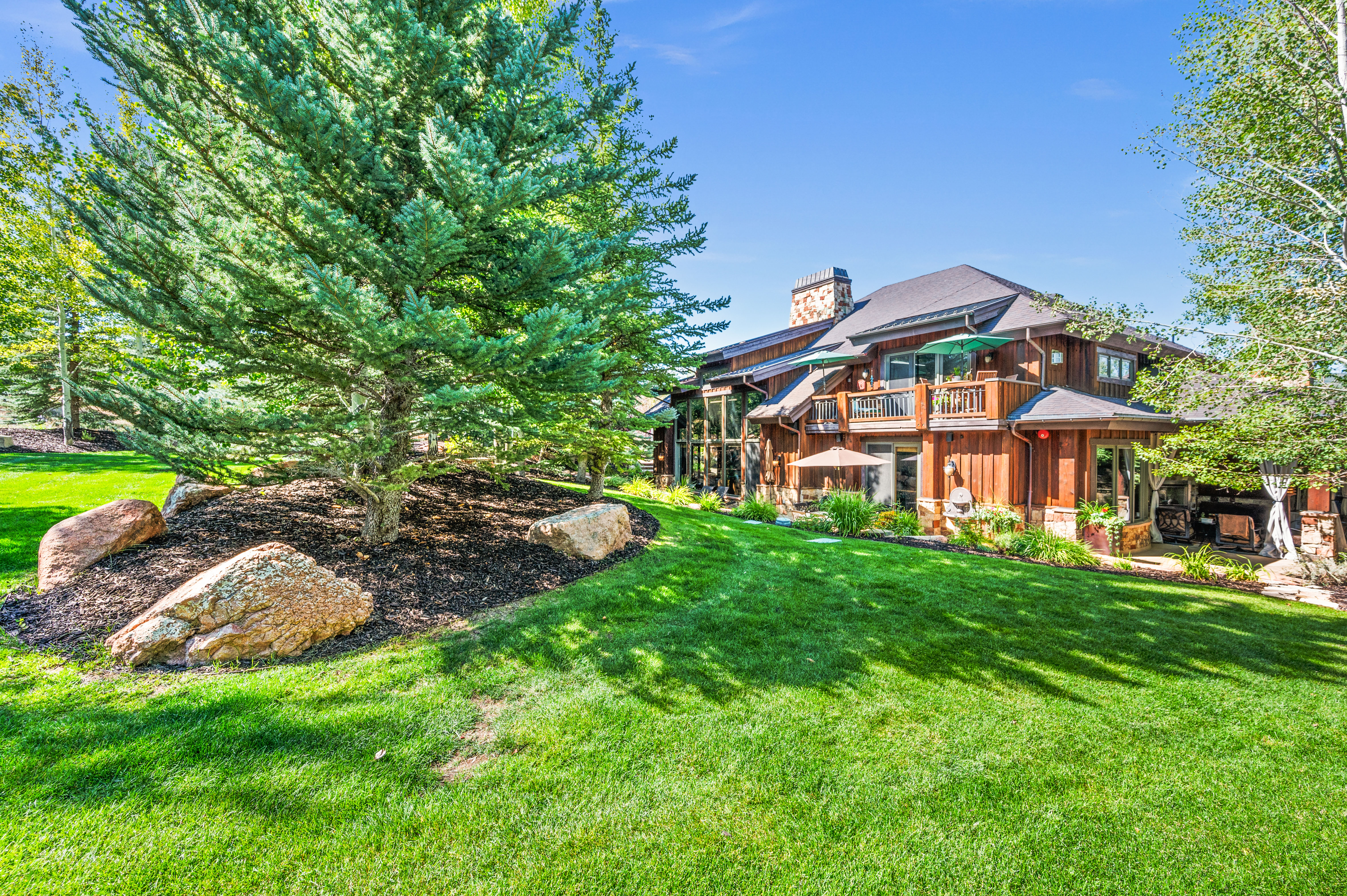 Rear view of property featuring a yard, a chimney, board and batten siding, and a balcony