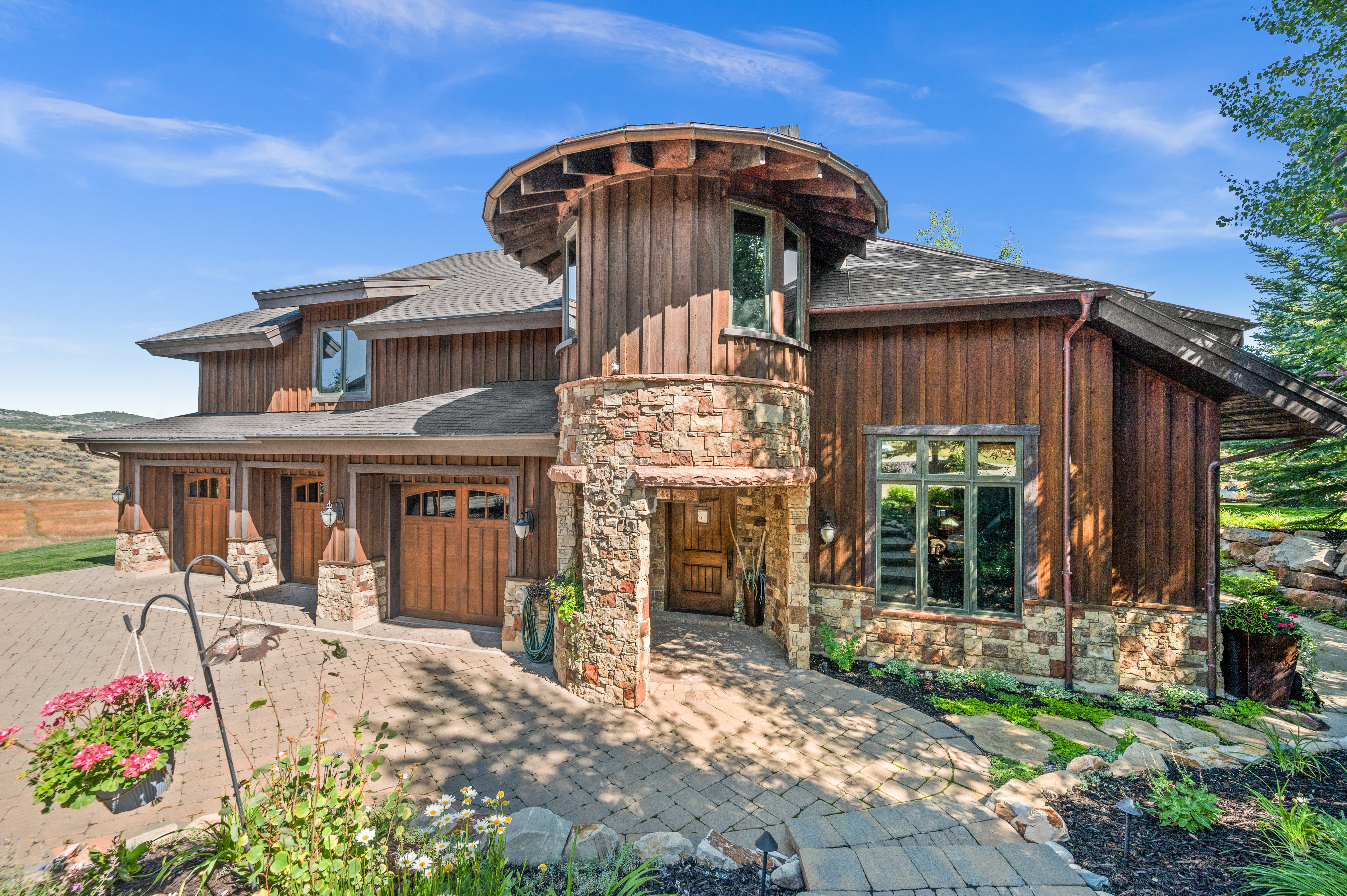 View of front facade featuring stone siding, a shingled roof, and a garage