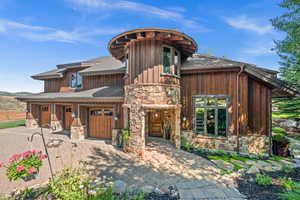 View of front facade featuring stone siding, a shingled roof, and a garage