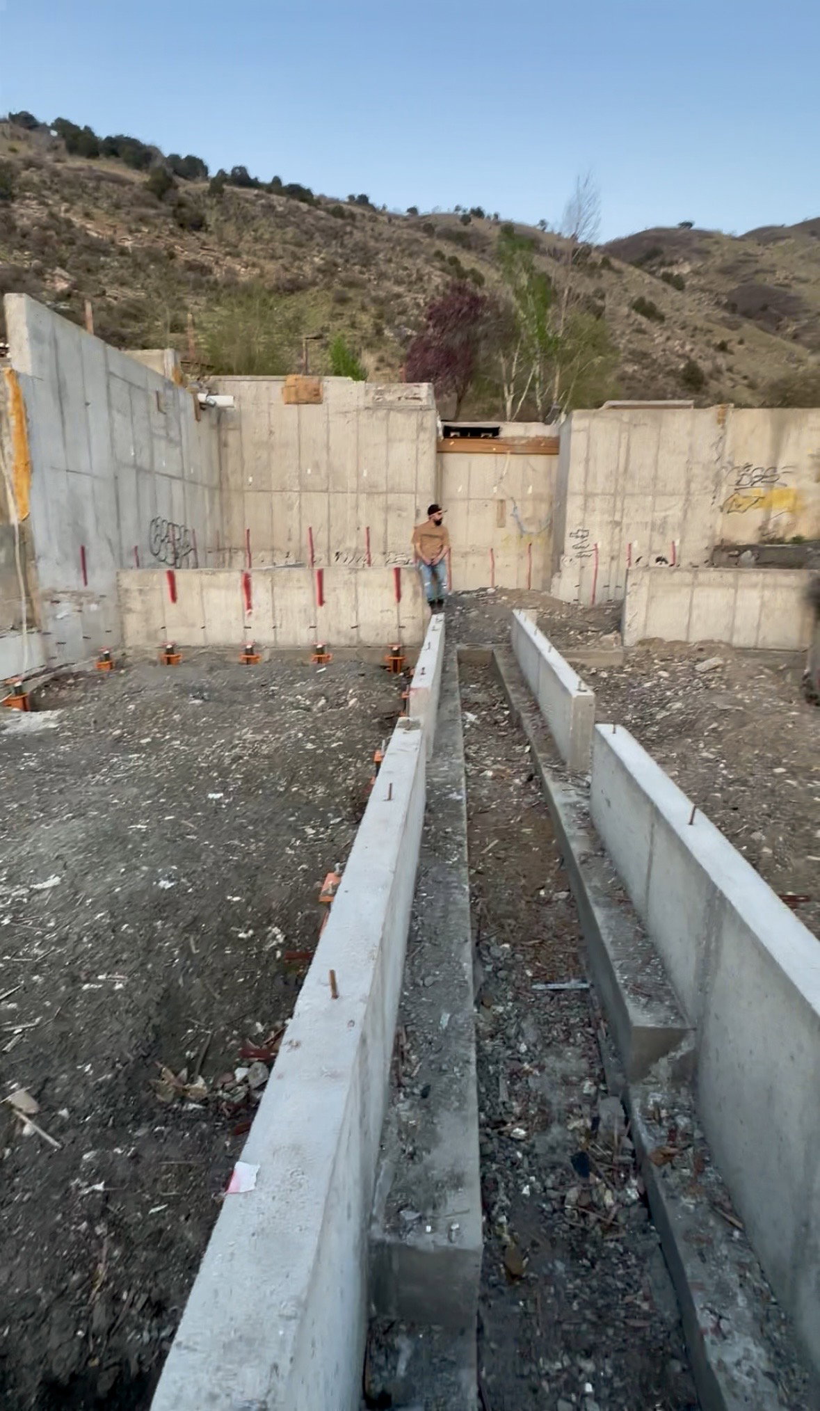 Foundational concrete walls with visible rebar and graded terrain