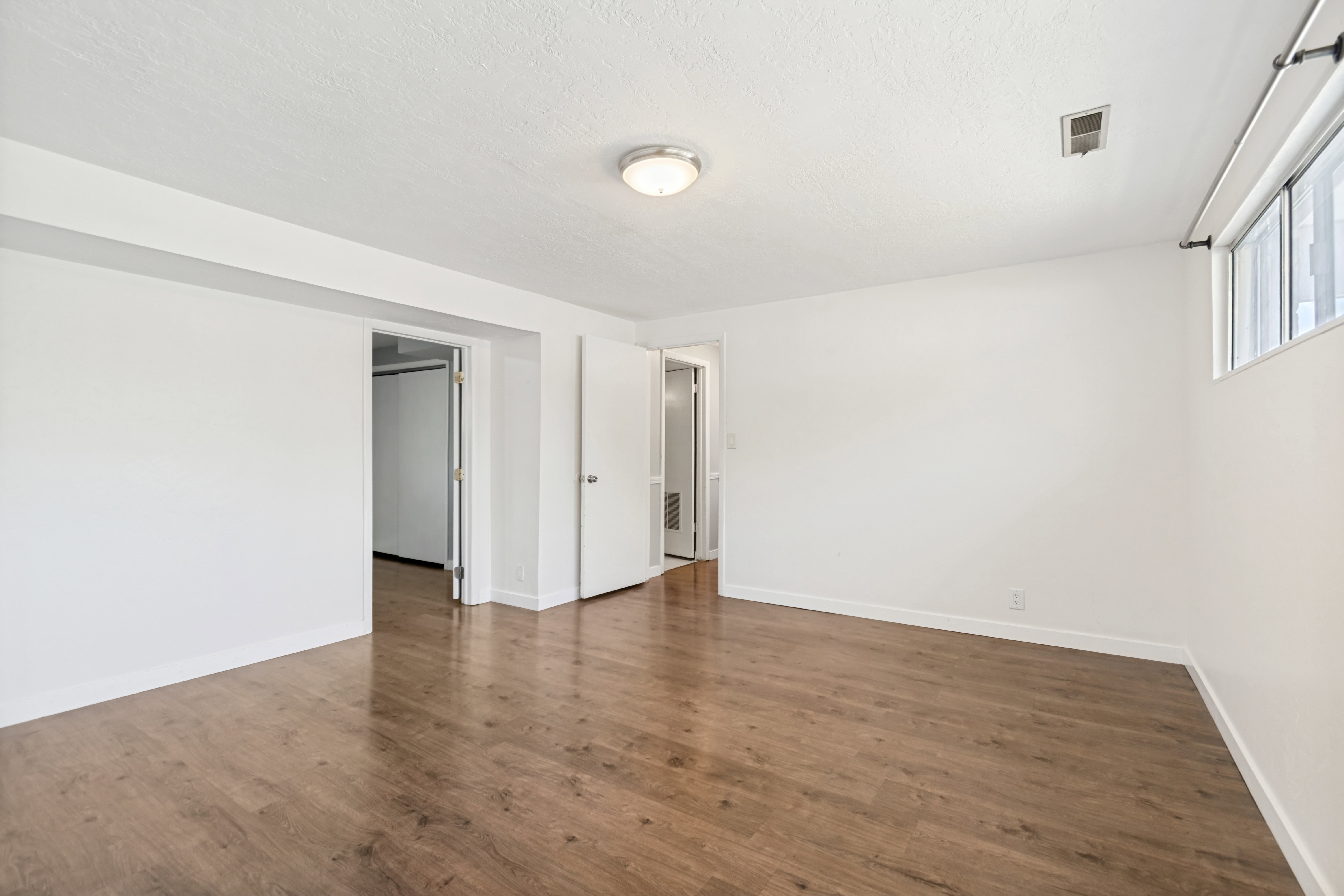 Spacious room featuring wood-finish flooring and a neutral color palette