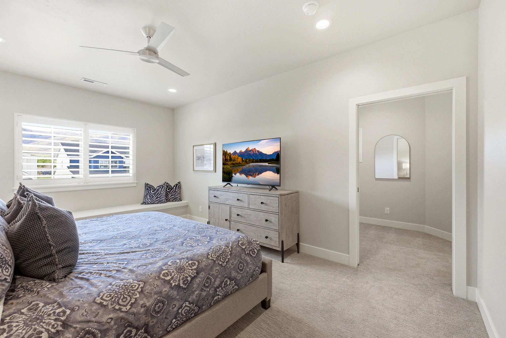Carpeted room featuring a built-in window bench, white plantation shutters, a ceiling fan with integrated lighting, recessed lighting, and a white trimmed doorway