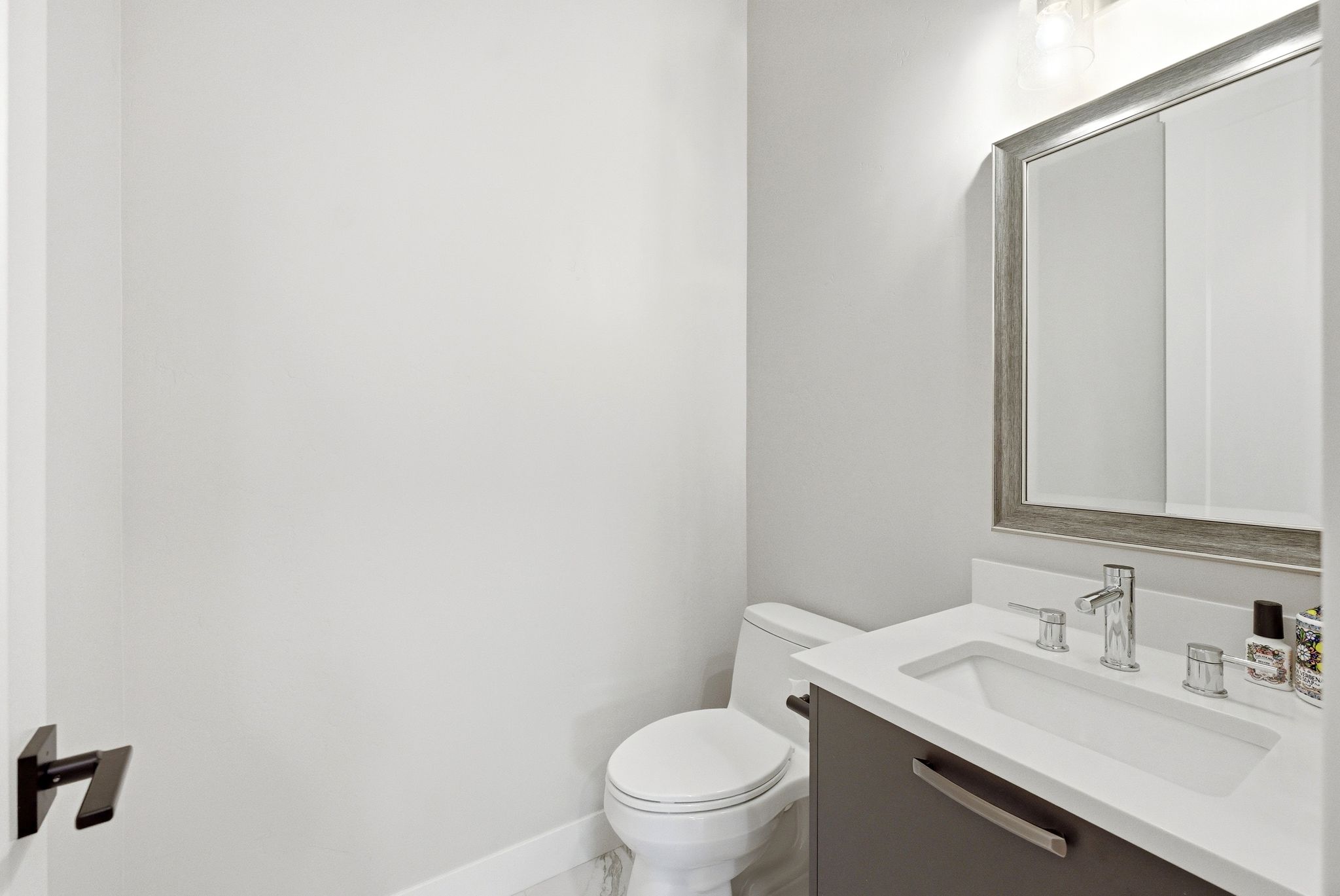Vanity with an integrated rectangular sink, chrome fixtures, and a framed mirror