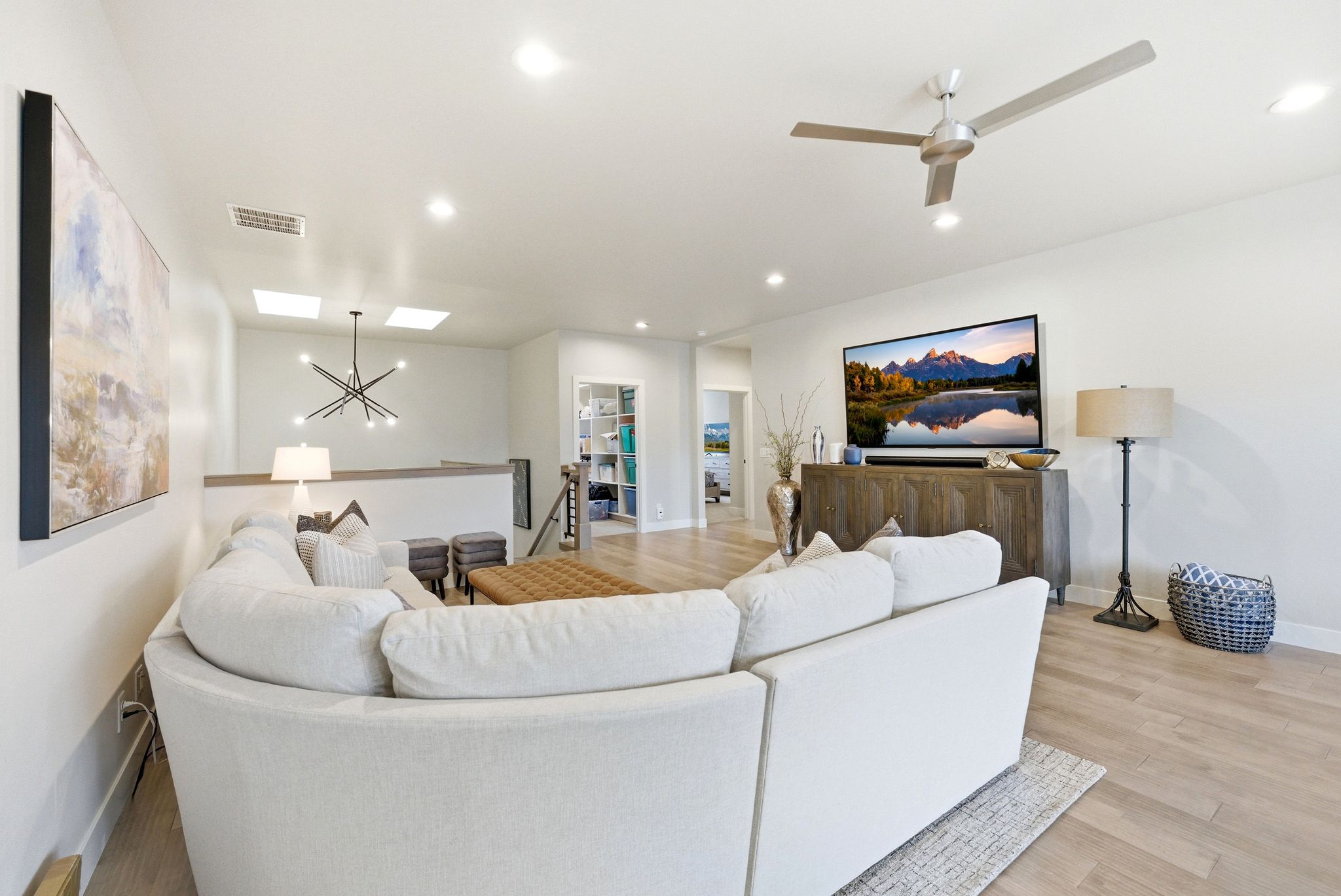 Open-concept living area featuring wood-finish flooring, a contemporary ceiling fan, recessed lighting, and a modern chandelier