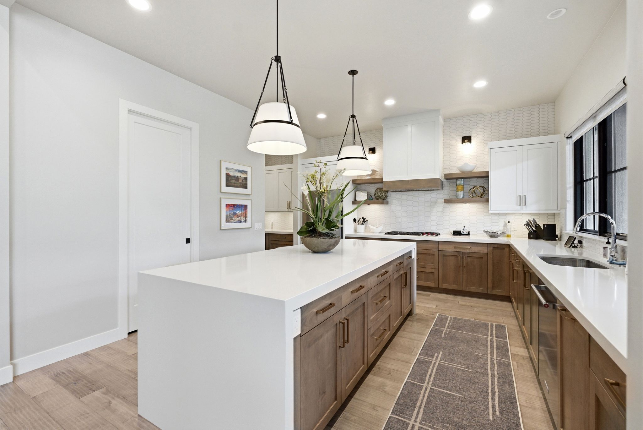 Spacious kitchen featuring a large white island with integrated storage, wood-finish flooring, recessed lighting, and a white tile backsplash
