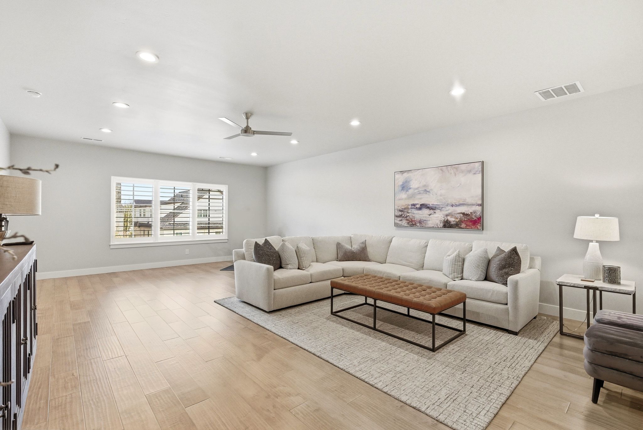 Spacious living area featuring light wood-finish flooring, recessed lighting, and a ceiling fan