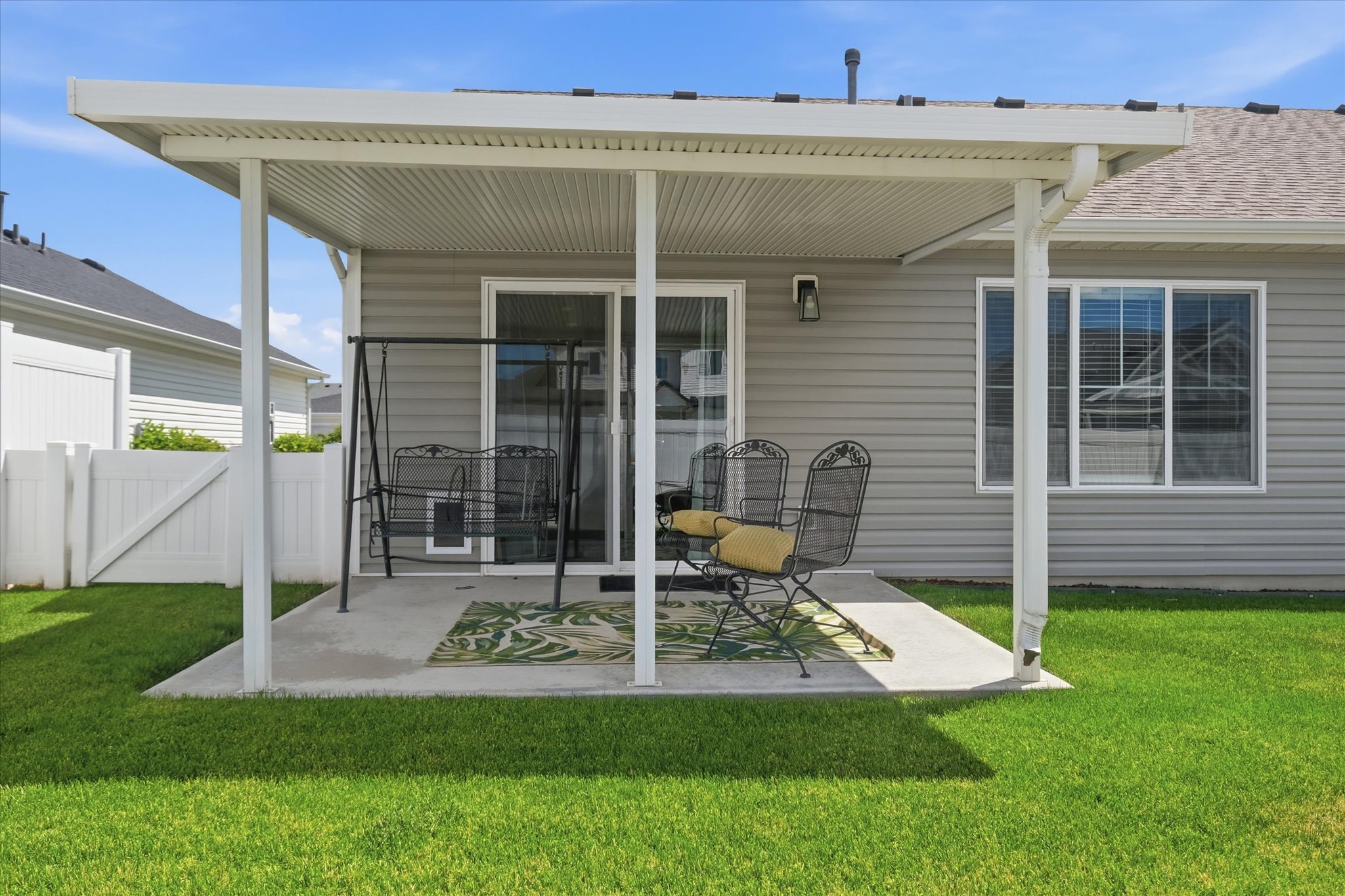 Concrete patio featuring a white pergola, gray siding, and a white vinyl fence